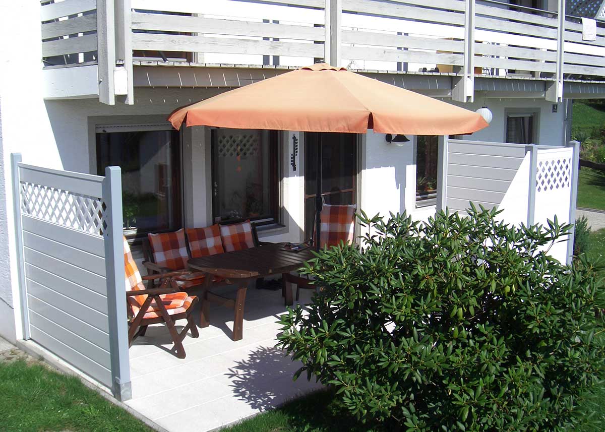 weiß grauer PVC Sichtschutz Trennwand mit Rankgitter auf kleiner Terrasse