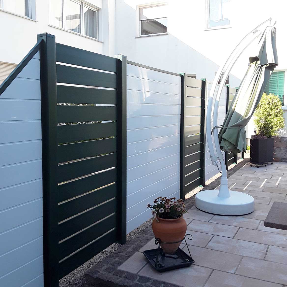 ECOLINE - Terrassensichtschutz mit Zierelementen in Anthrazit Sichtschutzzaun aus Kunststoff PVC in Anthrazit und Weiß auf einer Terrasse