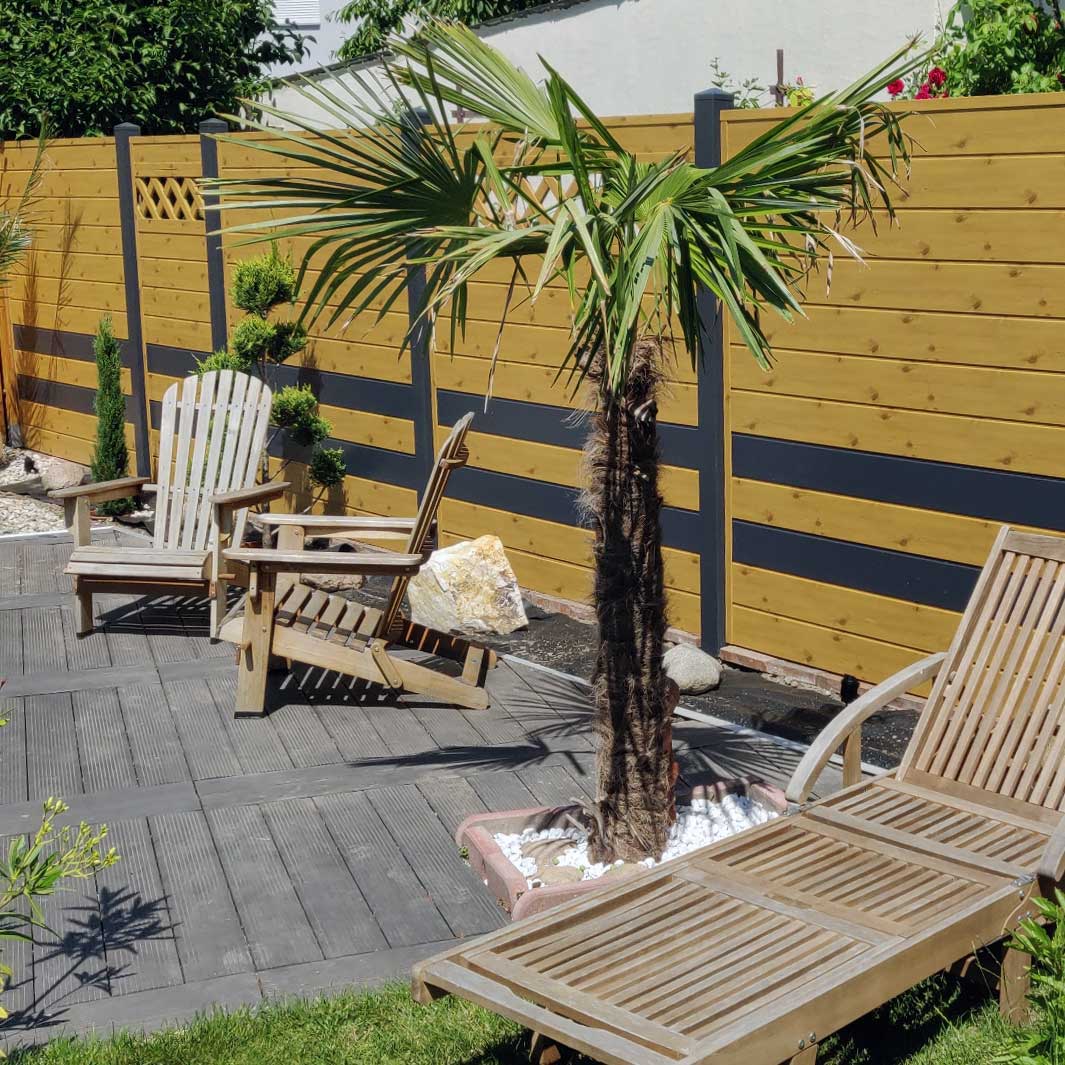 ECOLINE - zahlreiche Gestaltungmöglichkeiten, in Astfichte/Anthrazit Sichtschutzzaun aus Kunststoff PVC in Astfichte und Anthrazit auf einer Sommerterrasse mit Palmen