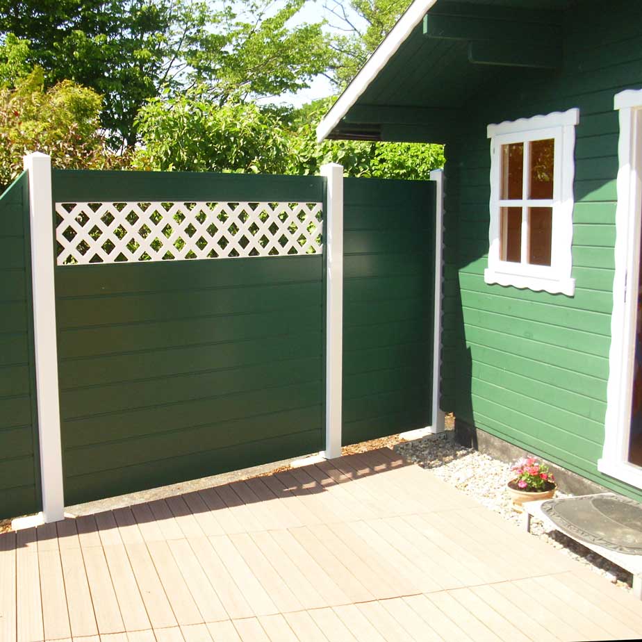 ECOLINE -Sichtschutz im natürlichem Moosgrün, als RAL Farbe definiert, für den passenden Gartenhäuschen-Anstrich grüner Sichtschutzzaun mit Rankgitter in weiß und weißen Pfosten auf einer Gartenterrasse vor der Laube
