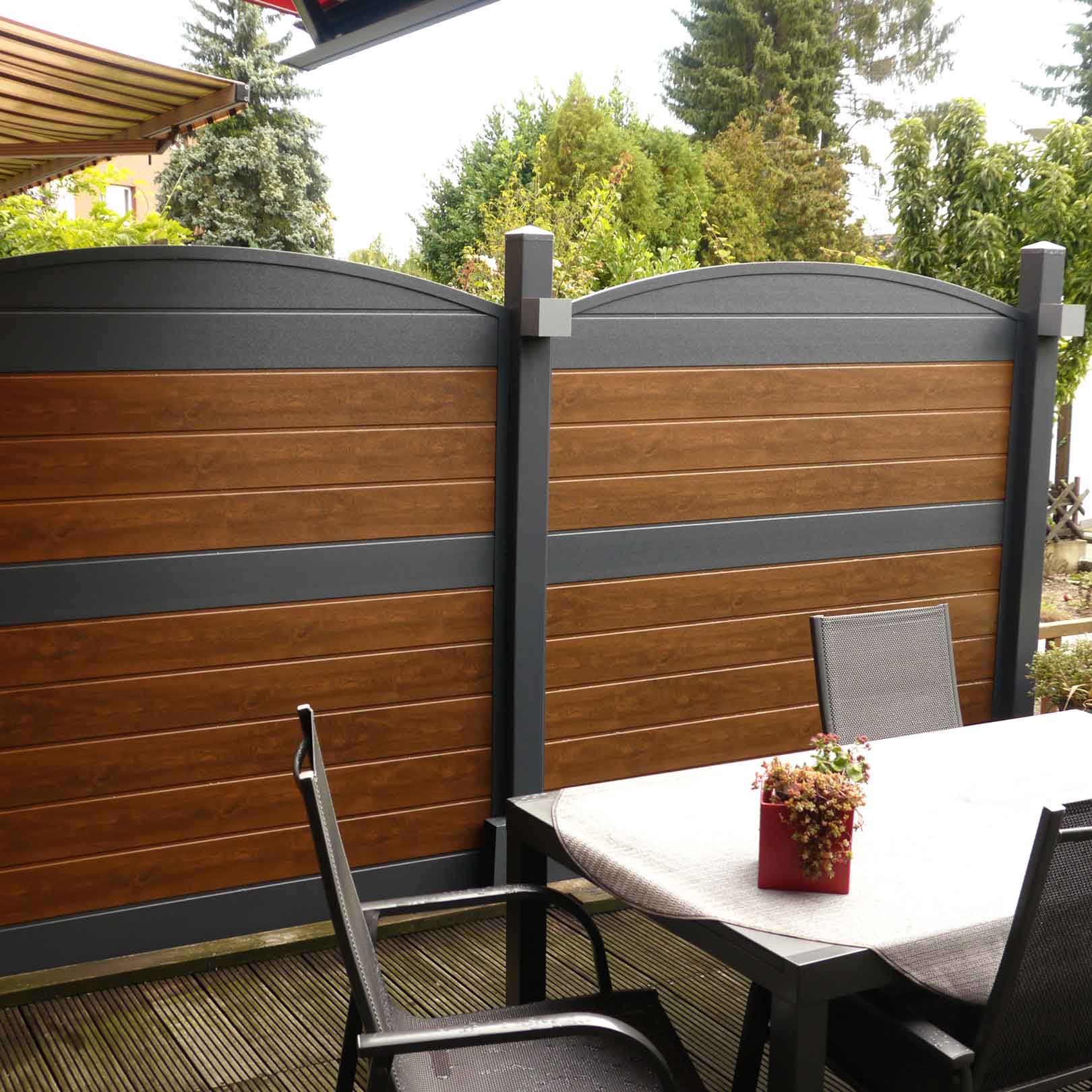 ECOLINE - der Runde Schliff für gemütliche Sitzecken Sichtschutzzaun aus Kunststoff PVC in Nussbaum und Anthrazit auf einer Terrasse