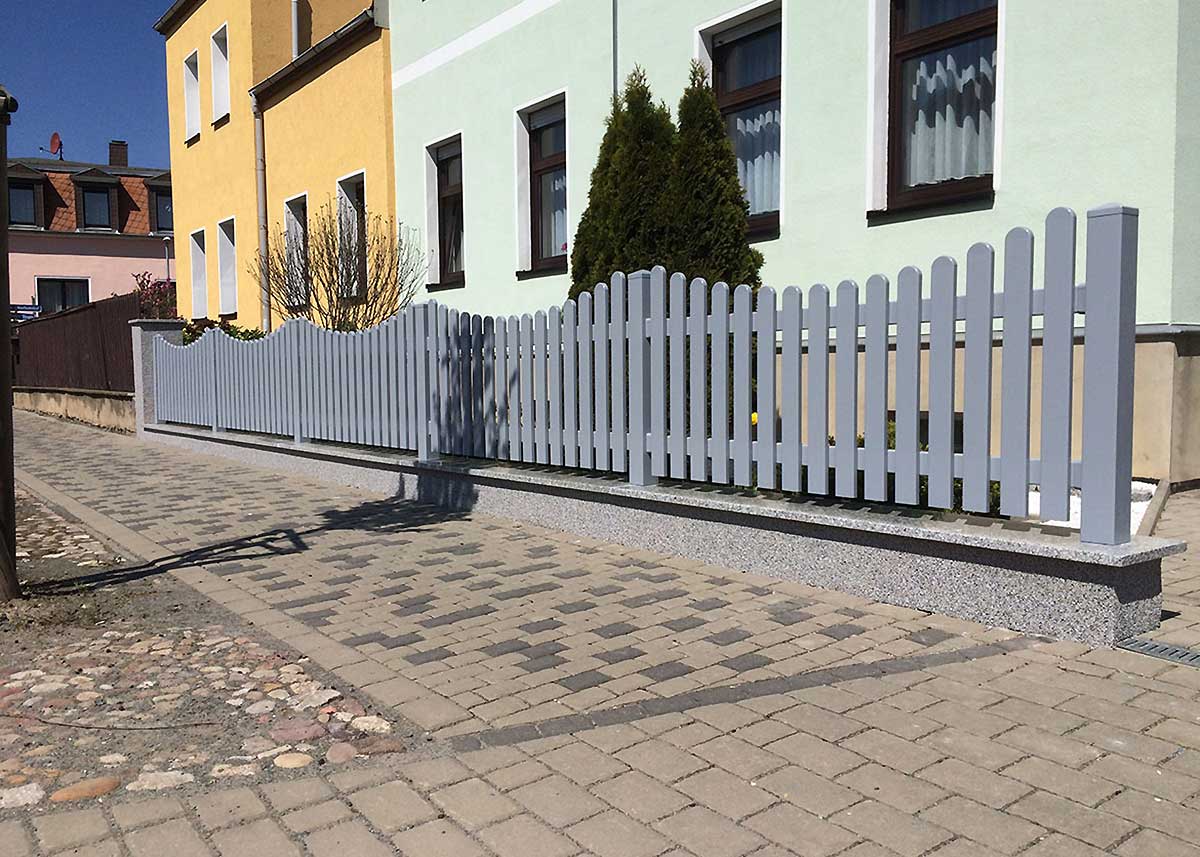 hellgrauer moderner Lattenzaun mit Unterbogen im Vorgarten, PVC-Zaun grau zum Aufdübeln, Kunststoffzaun in Silbergrau