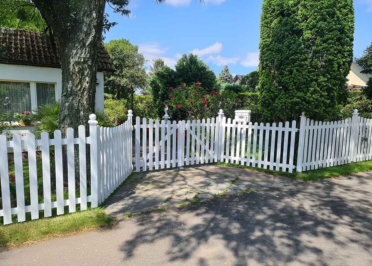 Gartenzaun in Weiß als Lattenzaun mit Unterbogen im Vorgarten, mit doppel-flügeligen Einfahrtstor
