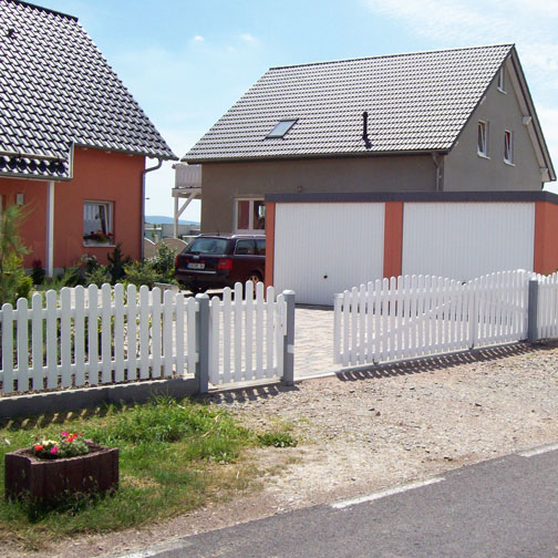 Lattenzaun mit großen Schiebetor in der Hofeinfahrt, in weiß